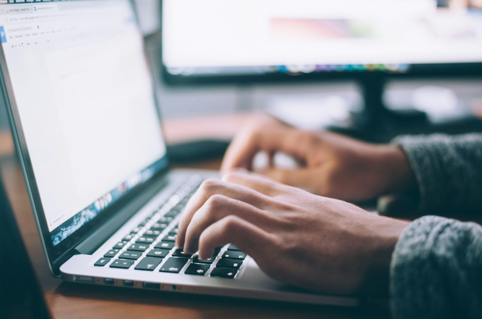 Hands typing on a silver laptop