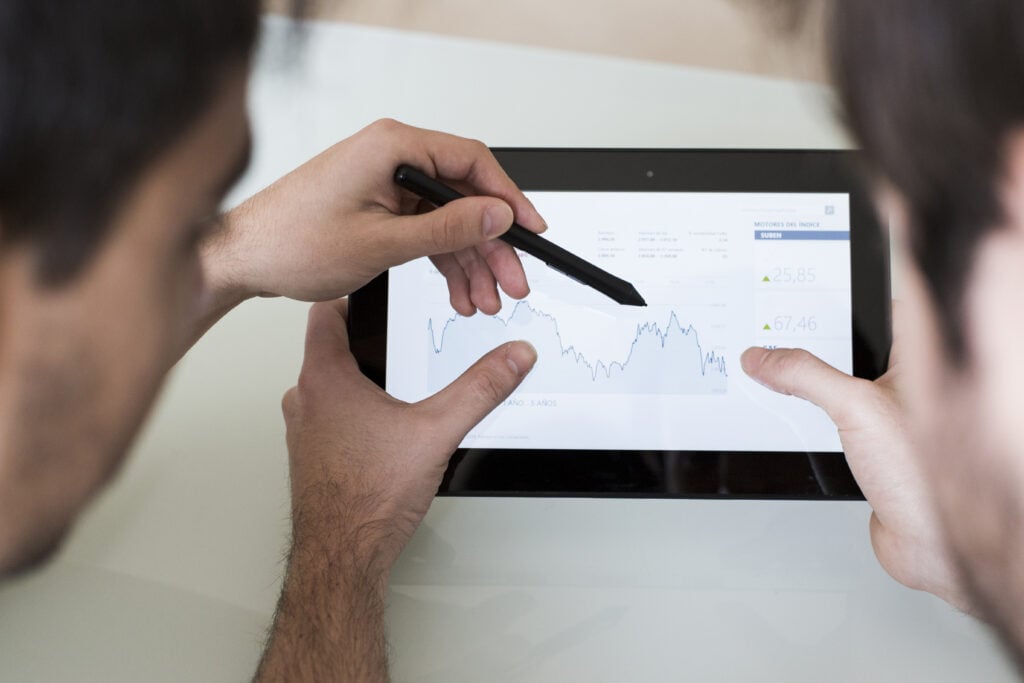 A close-up of people analyzing a rising/falling trend line on a screen
