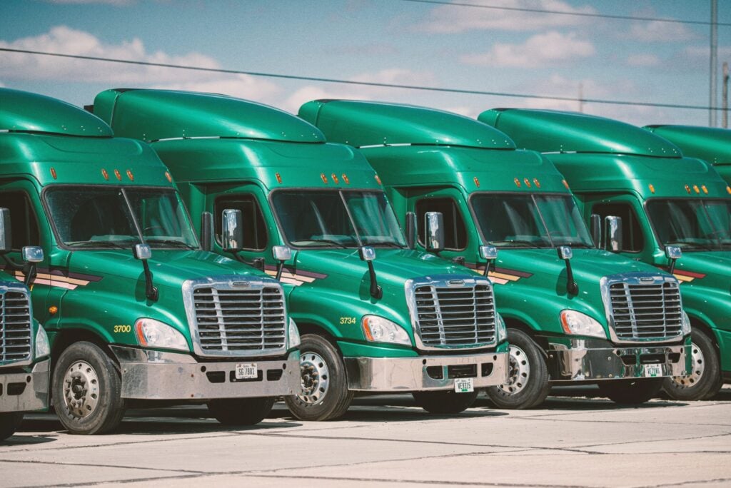 Row of green semi-trucks parked fleet