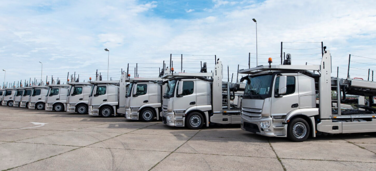 Row of car-carrier trucks parked in a fleet yard