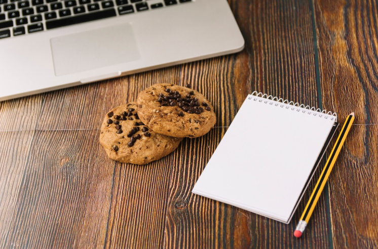 Cookies next to a notebook and laptop illustrating cookie consent