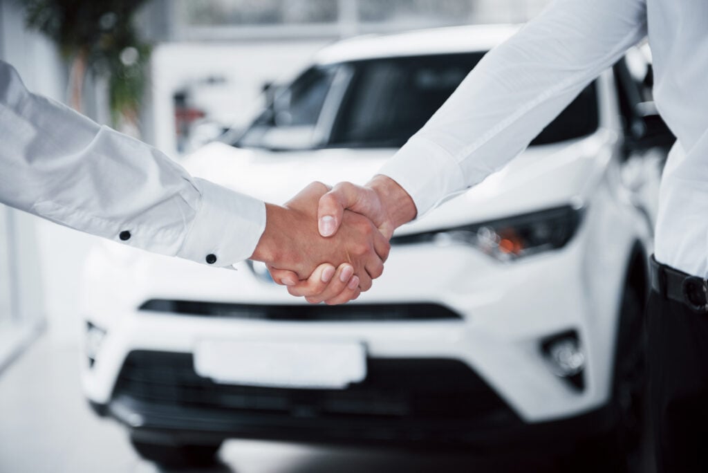 Two employees agreeing in front of a car