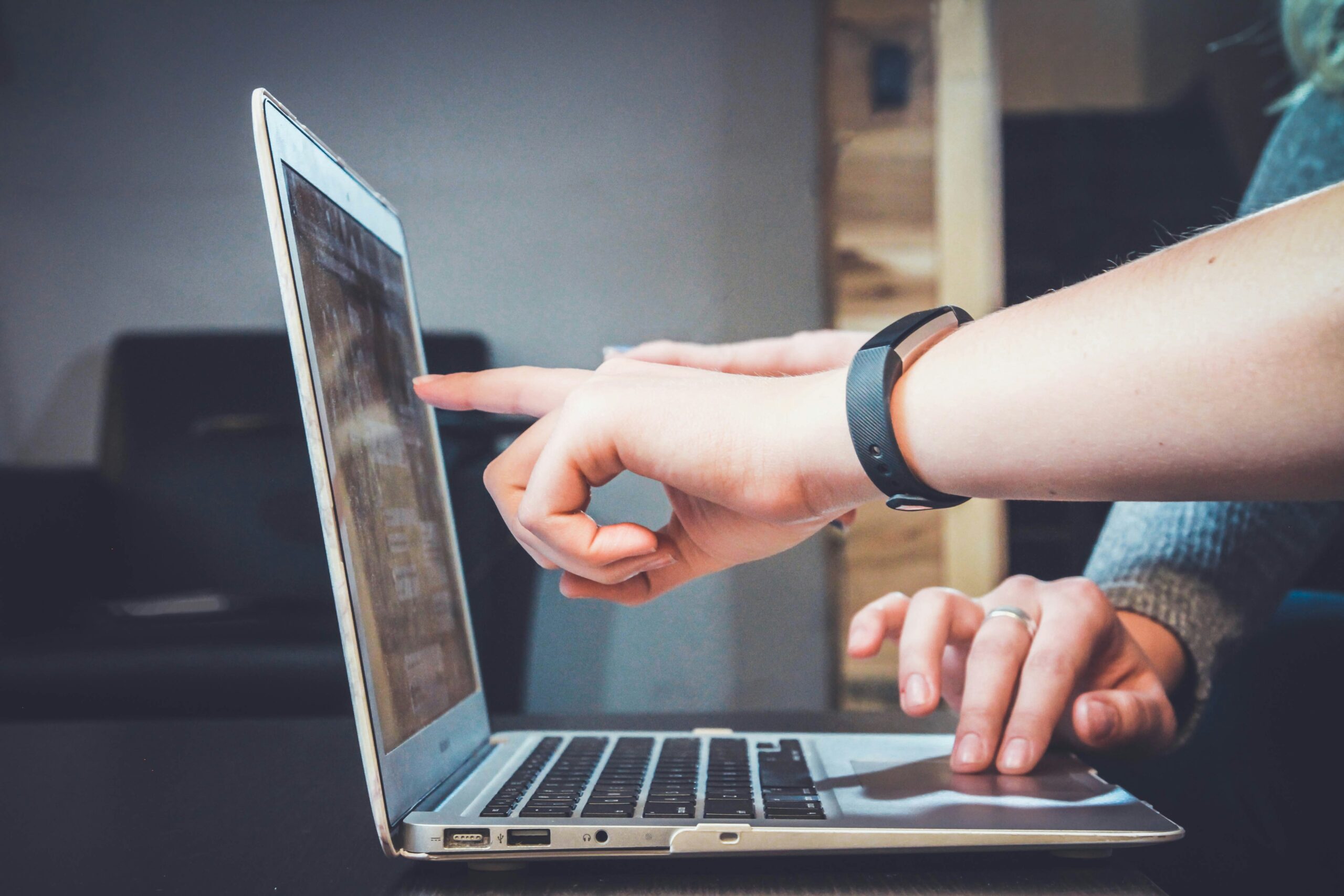 Person pointing at laptop screen during meeting