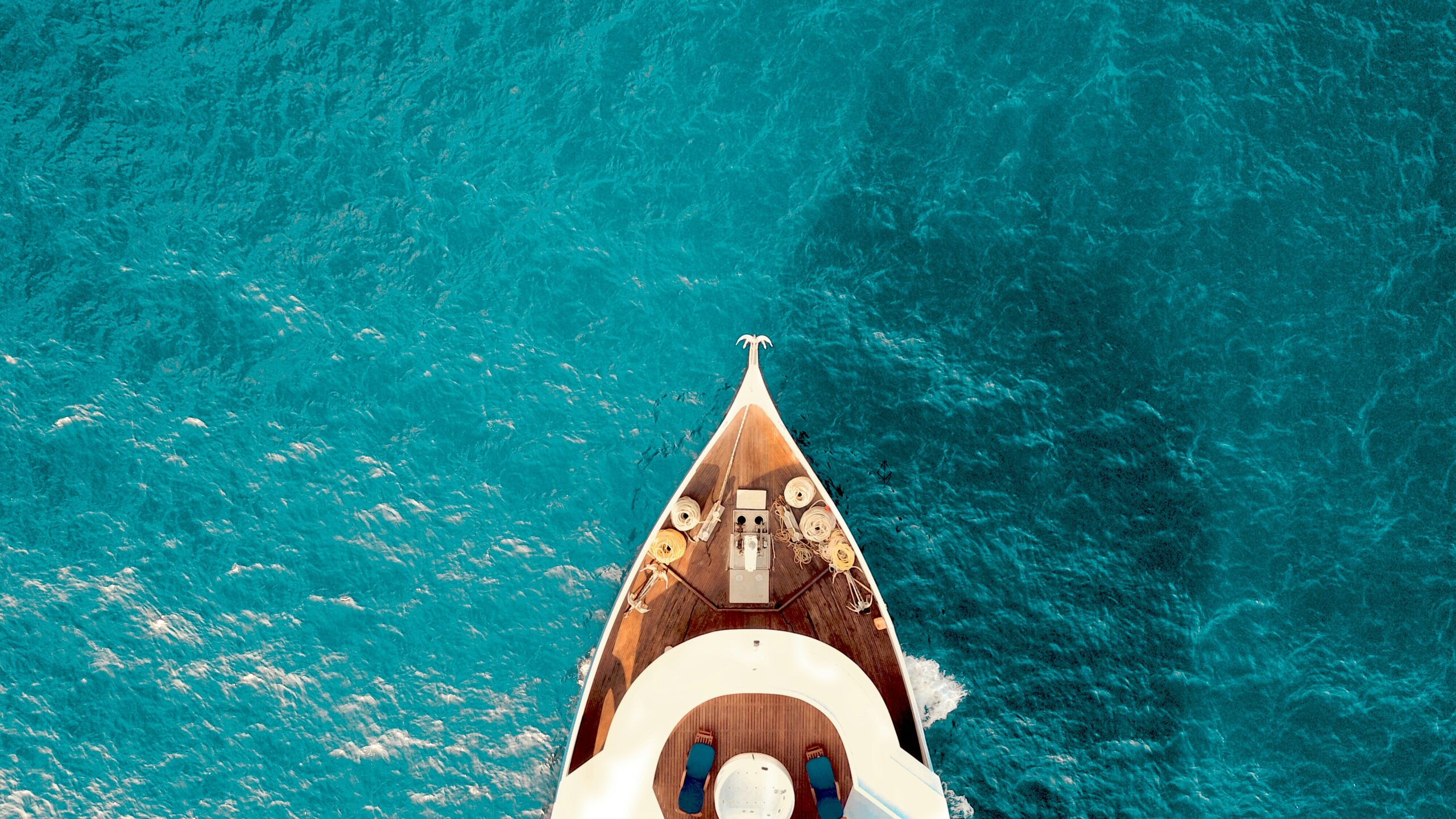 Aerial view of luxury yacht bow sailing through bright turquoise water