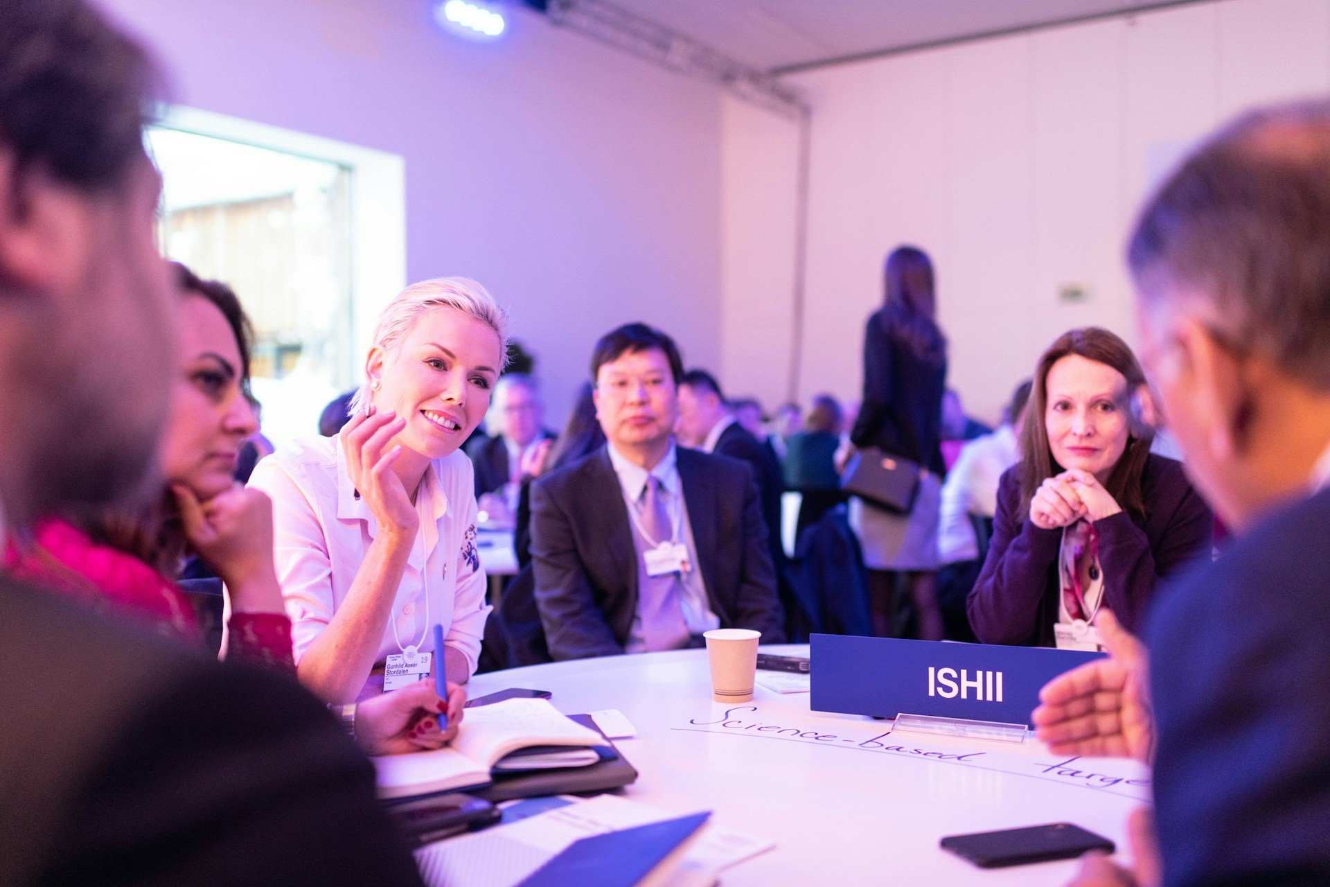 Group of professionals networking and smiling around a white conference table