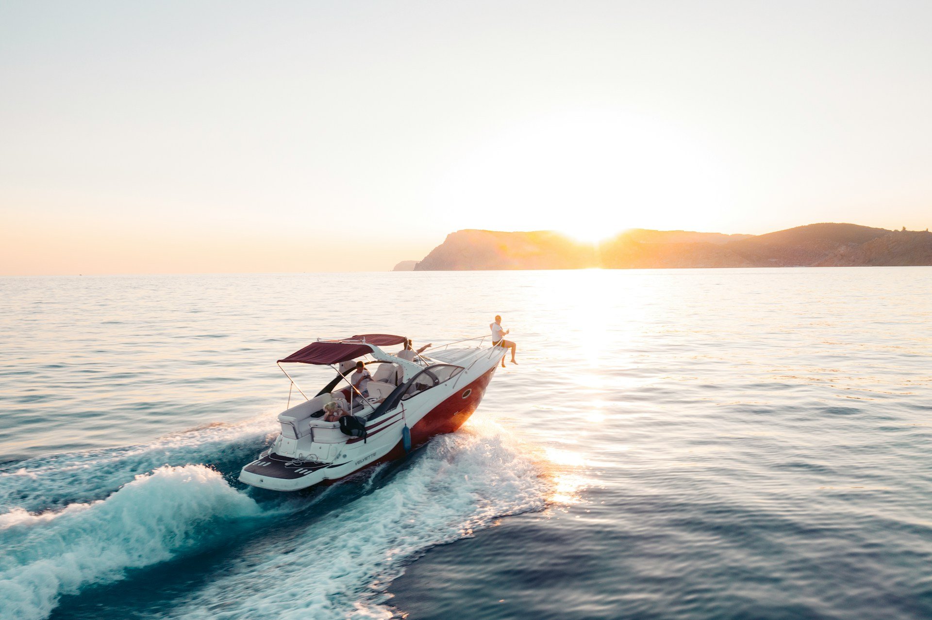 Speedboat cruising across the ocean at sunset near a coast