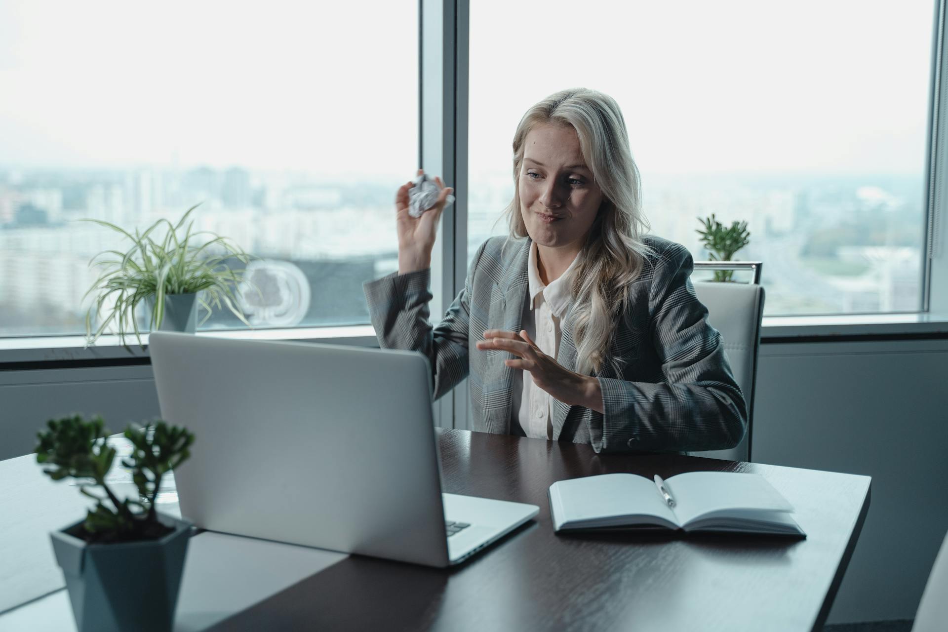 A fed up employee throwing rolled up paper toward a laptop screen