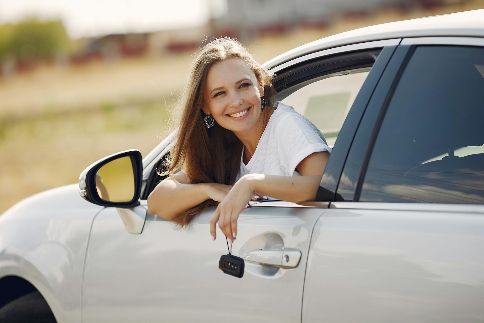 A woman smiling sitting inside a car