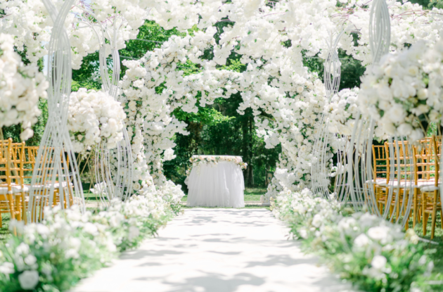 Elegant outdoor wedding ceremony with white floral arch and aisle